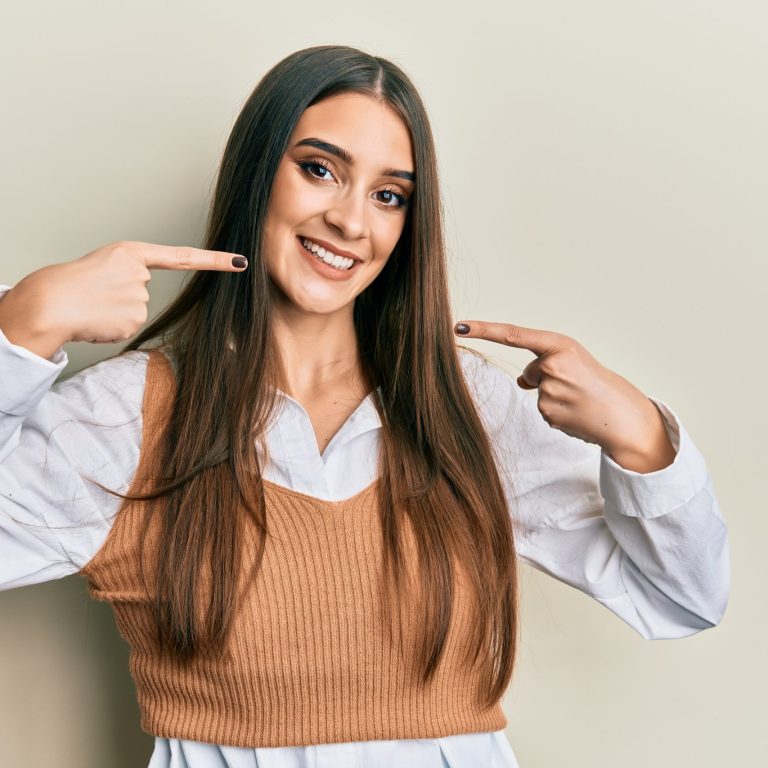 Beautiful brunette young woman wearing casual clothes smiling cheerful showing and pointing with fingers teeth and mouth. dental health concept.