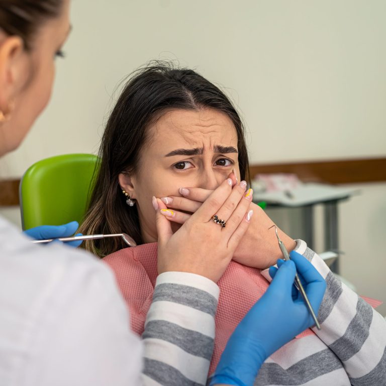 Woman afraid before dentisr procedure and covering mouth her hands, panic attack to pain. Concept of health care problem